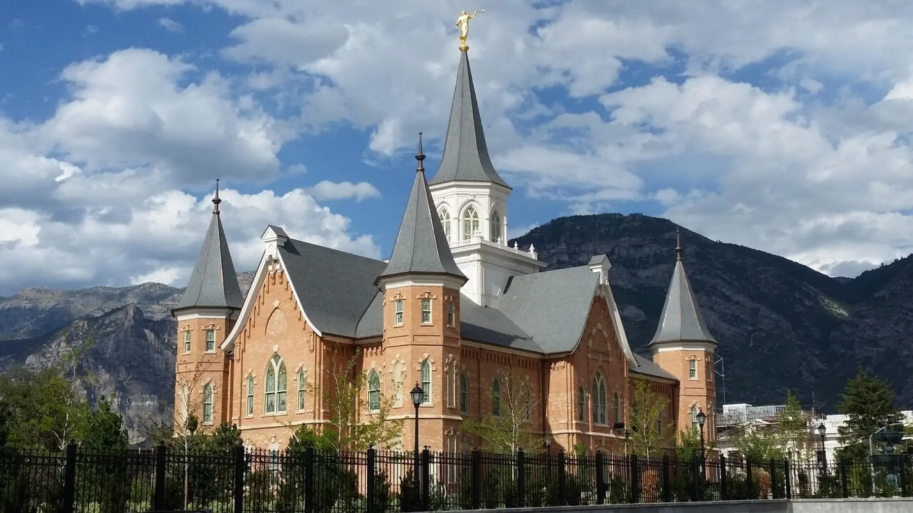 A historic brick building with tall spires and arched windows below the mountains in Provo, Utah
